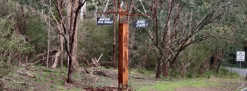 A metal totem at the entrance to Bend of Islands with COVID-related messages hanging from it.